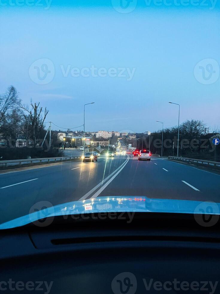 Evening road traffic with cars driving towards the city under a bright sky. photo