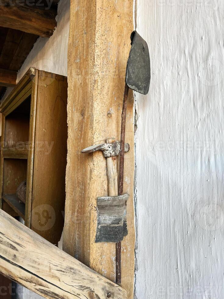 Rustic hand tools displayed on rough wooden supports in a historical setting photo