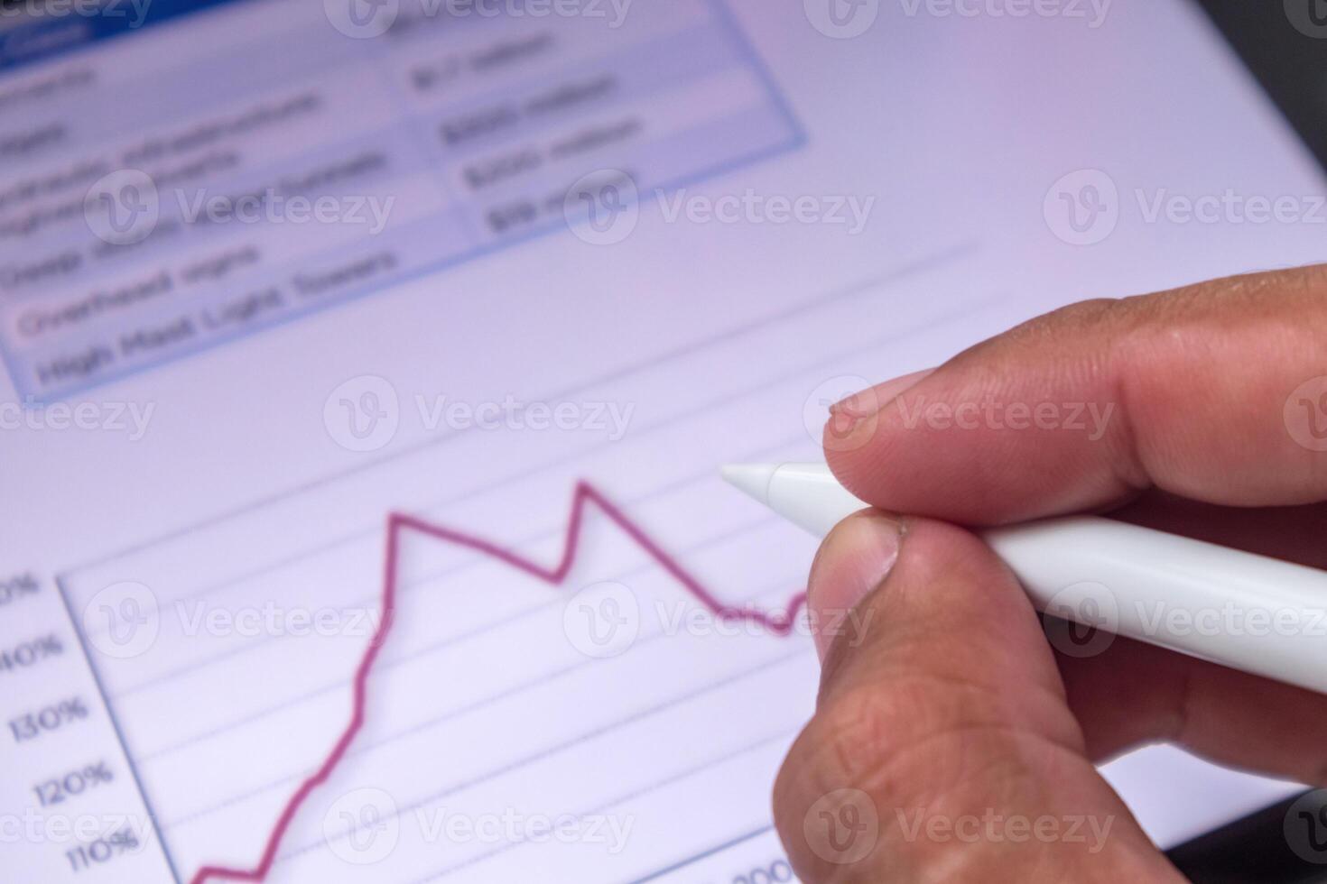 Businessman holding a pen pointing to business financial data analysis graphic report on digital screen photo