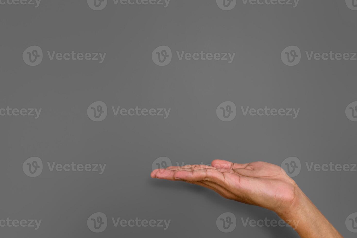 A man's hand with pose or gesture of giving, holding or offering something on gray background photo