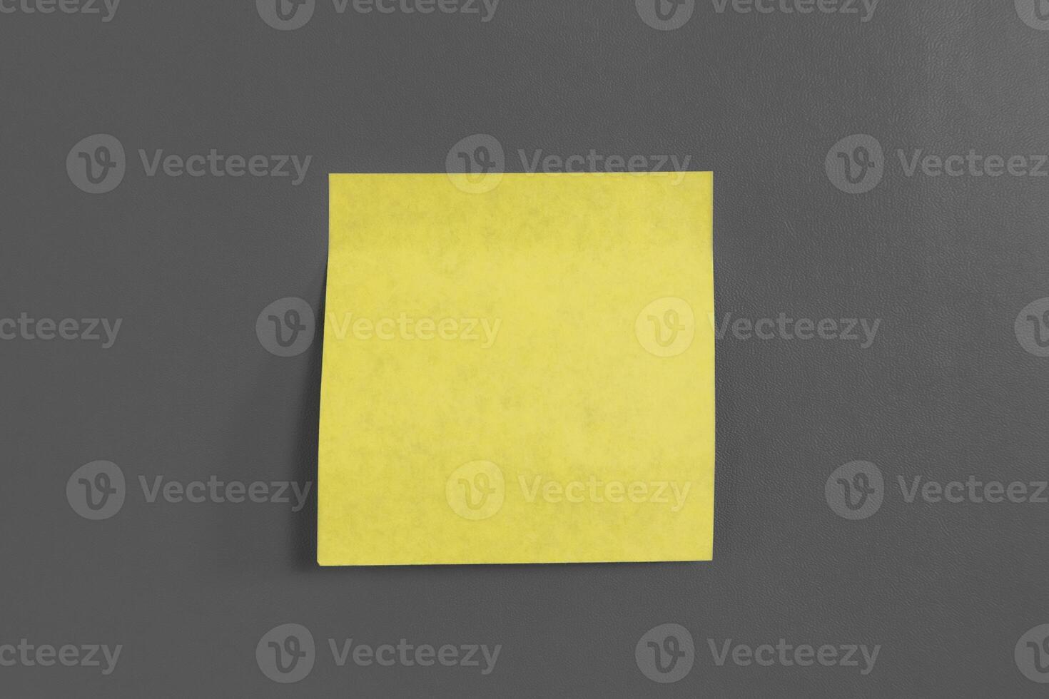 A blank yellow sticky note for writing a message on a gray background photo