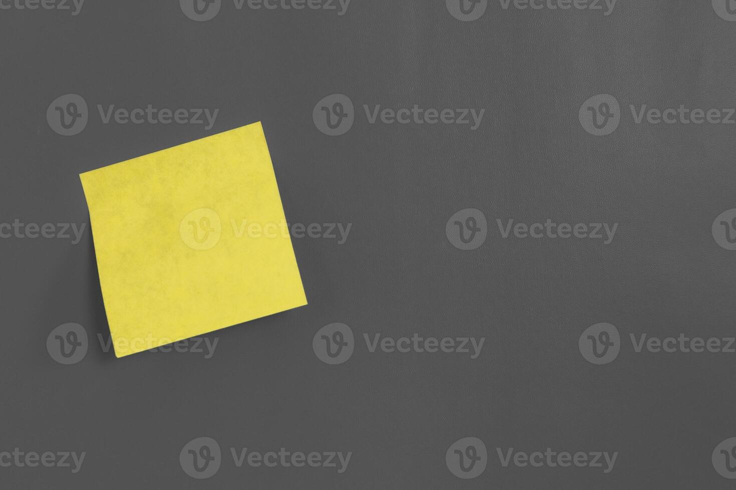 A blank yellow sticky note with copy space on a gray background photo