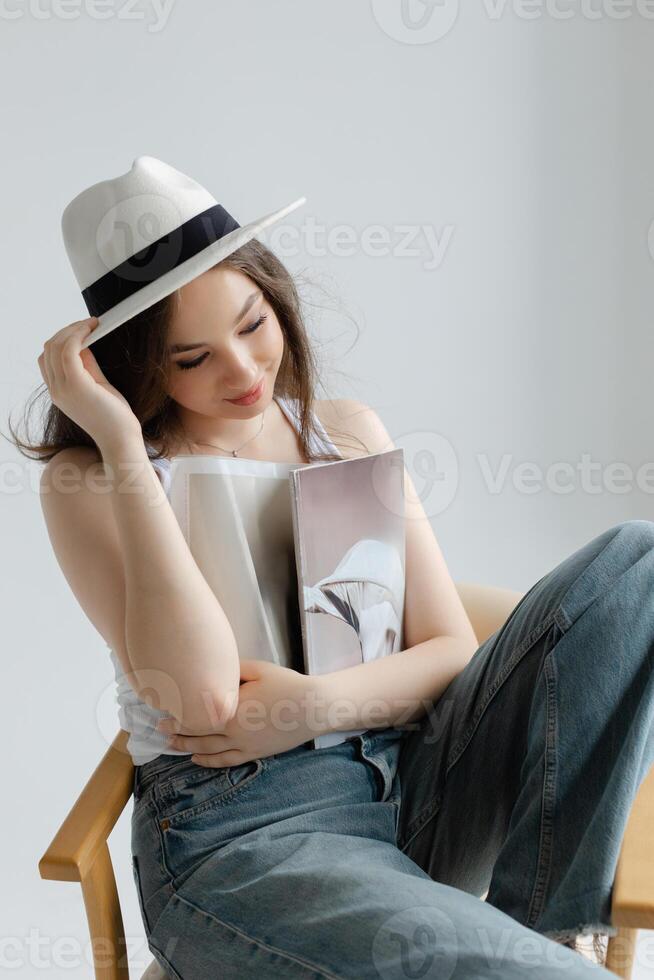 Young woman reading magazine sitting on chair. photo