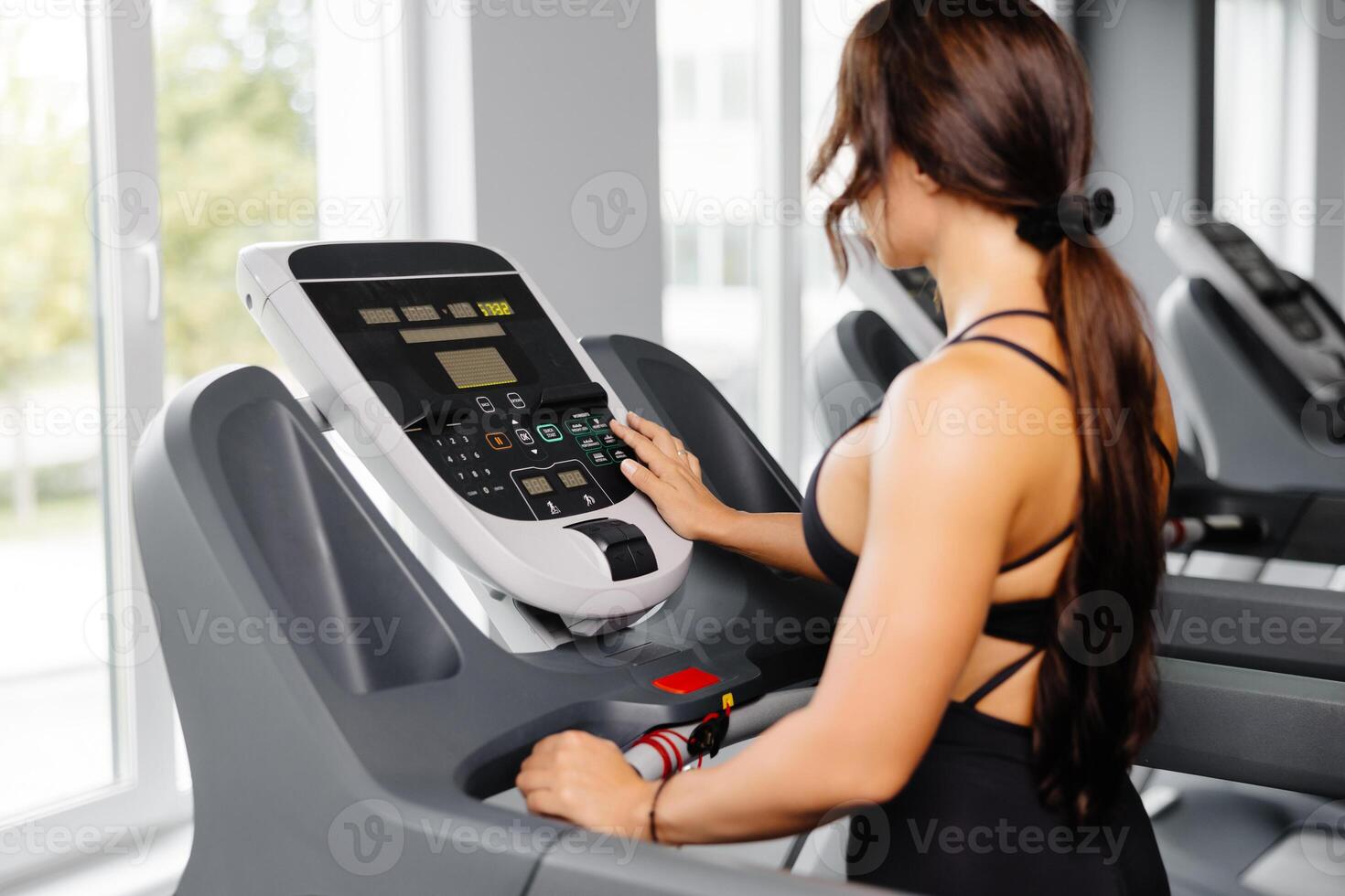 Young sports woman is working out in gym, she doing cardio training on treadmill. Running on treadmill. photo