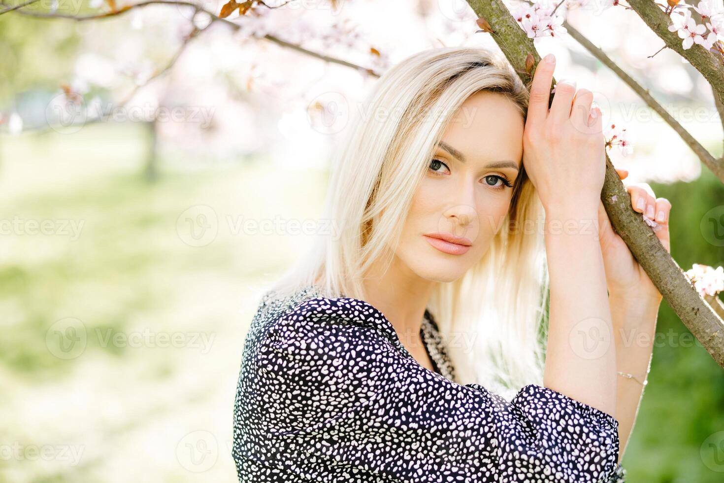 Beautiful blonde woman posing in spring blossom park photo