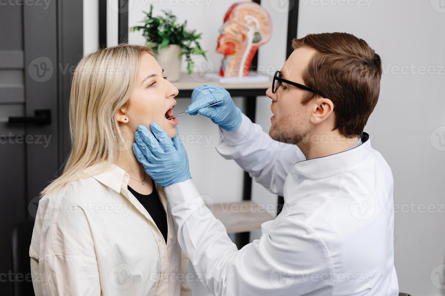 Doctor using inspection spatula to examine patient throat. ENT doctor doing throat exam of a woman photo