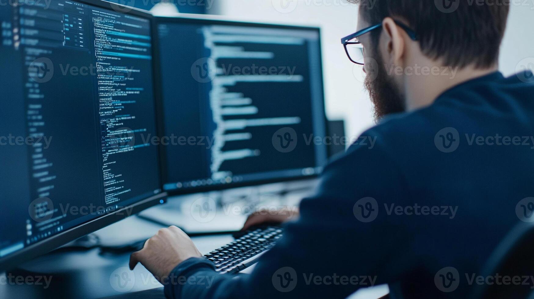 A man is working on two computer screens photo