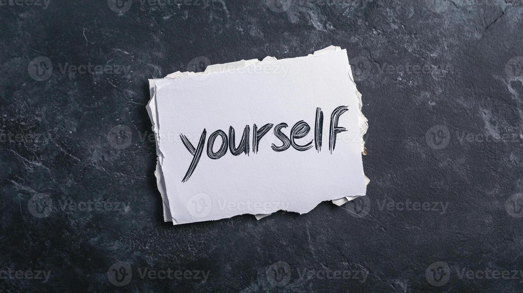 Self-concept concept on torn paper with the word yourself written on it, on a dark background photo