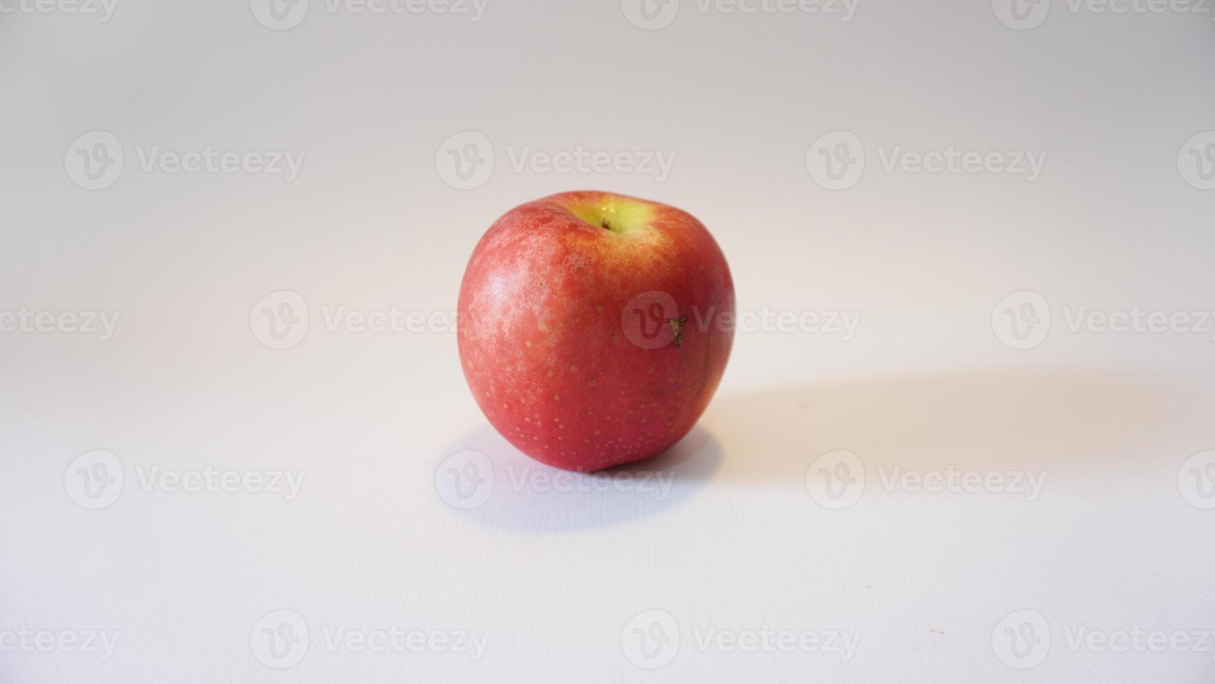 A red apple sitting on a white surface photo