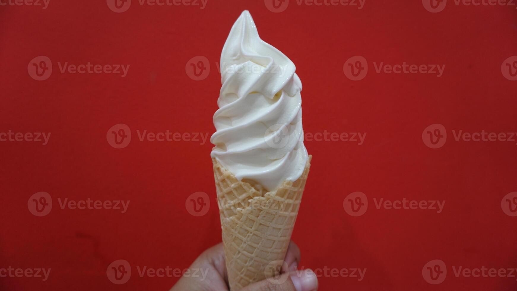 A hand holding a waffle cone with whipped cream photo