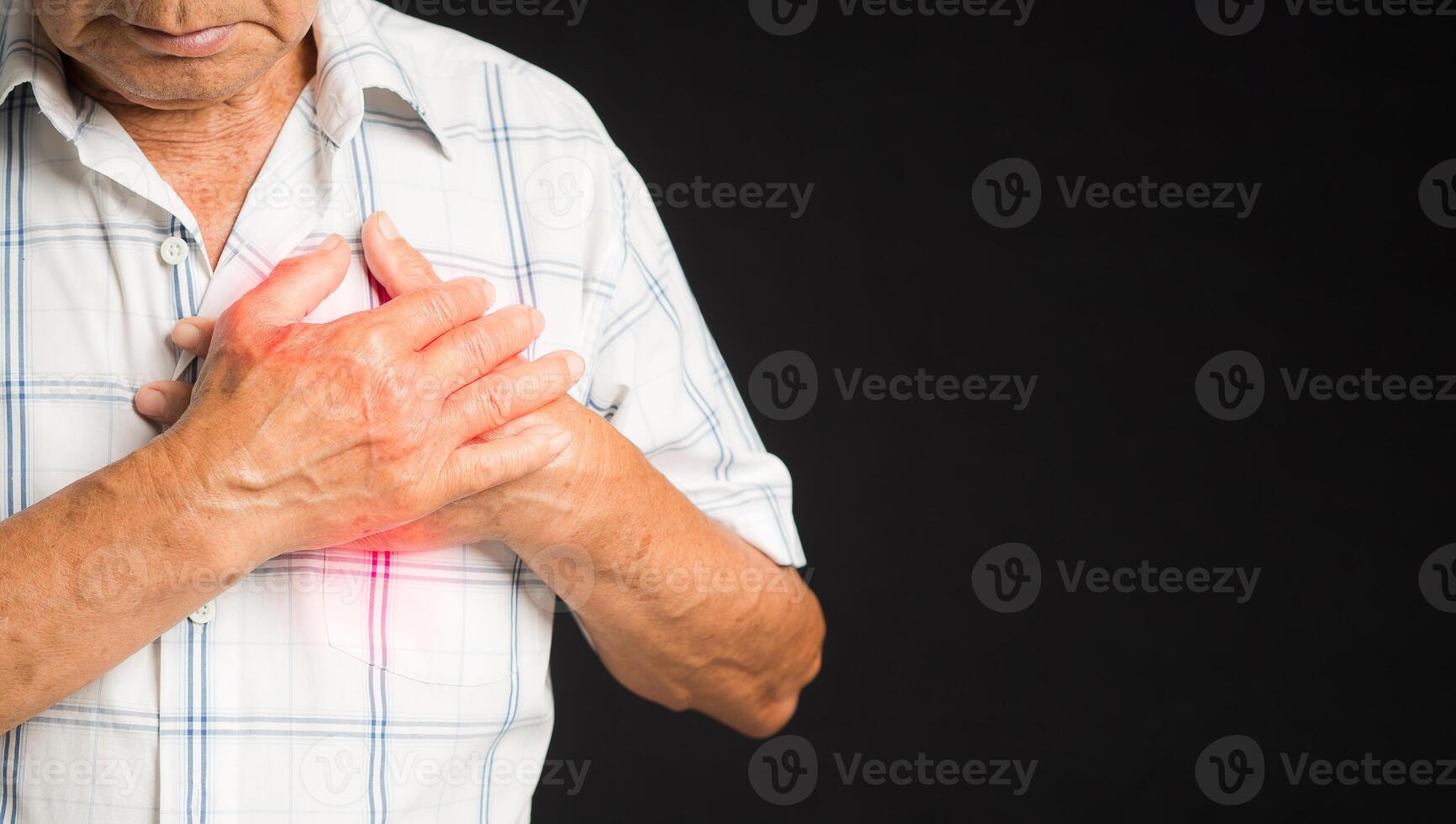 Senior man is suffering from chest pain while standing on a black background photo