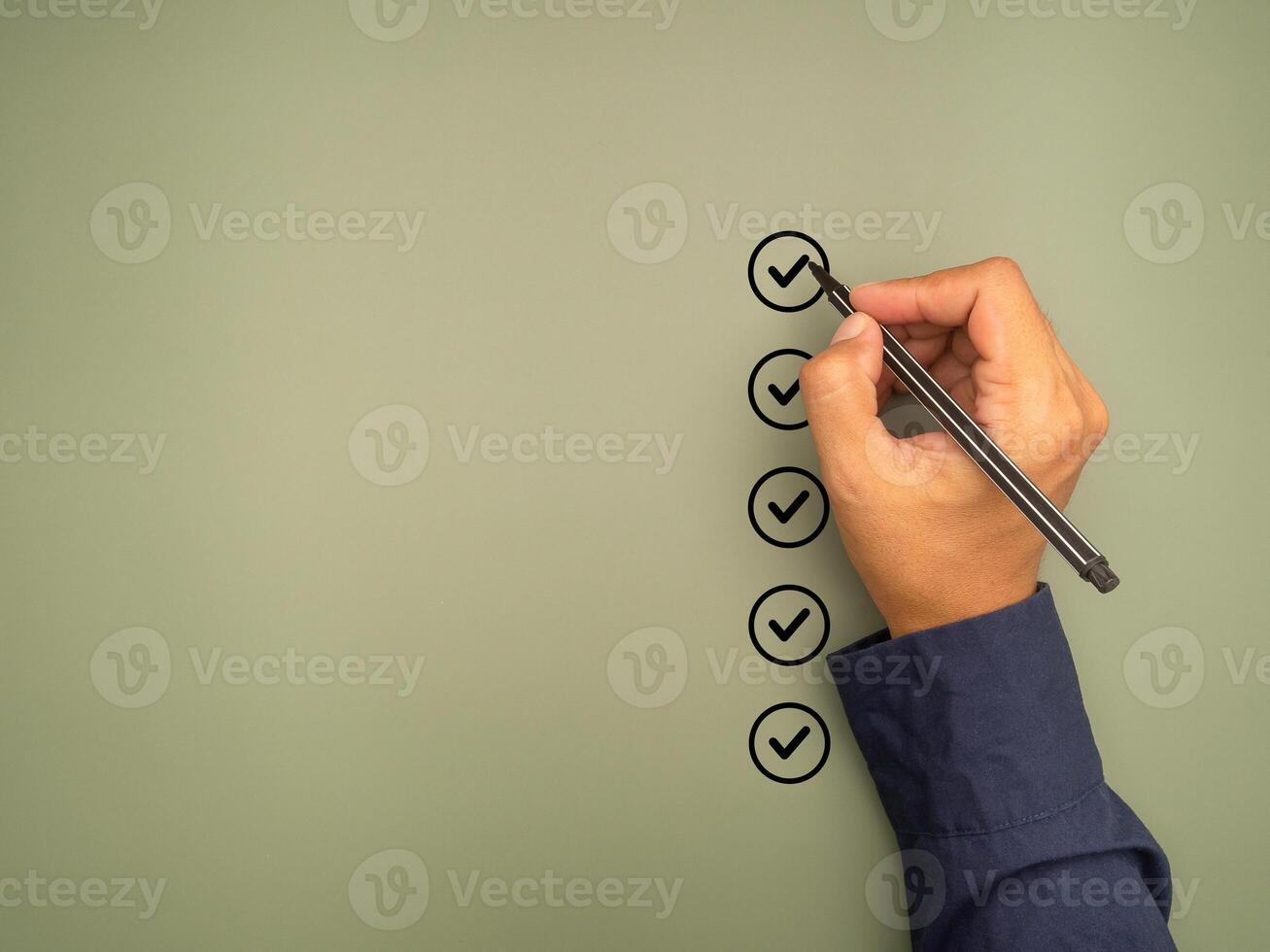 Hand holding a pen check-marking on the checklist box on a green background. photo