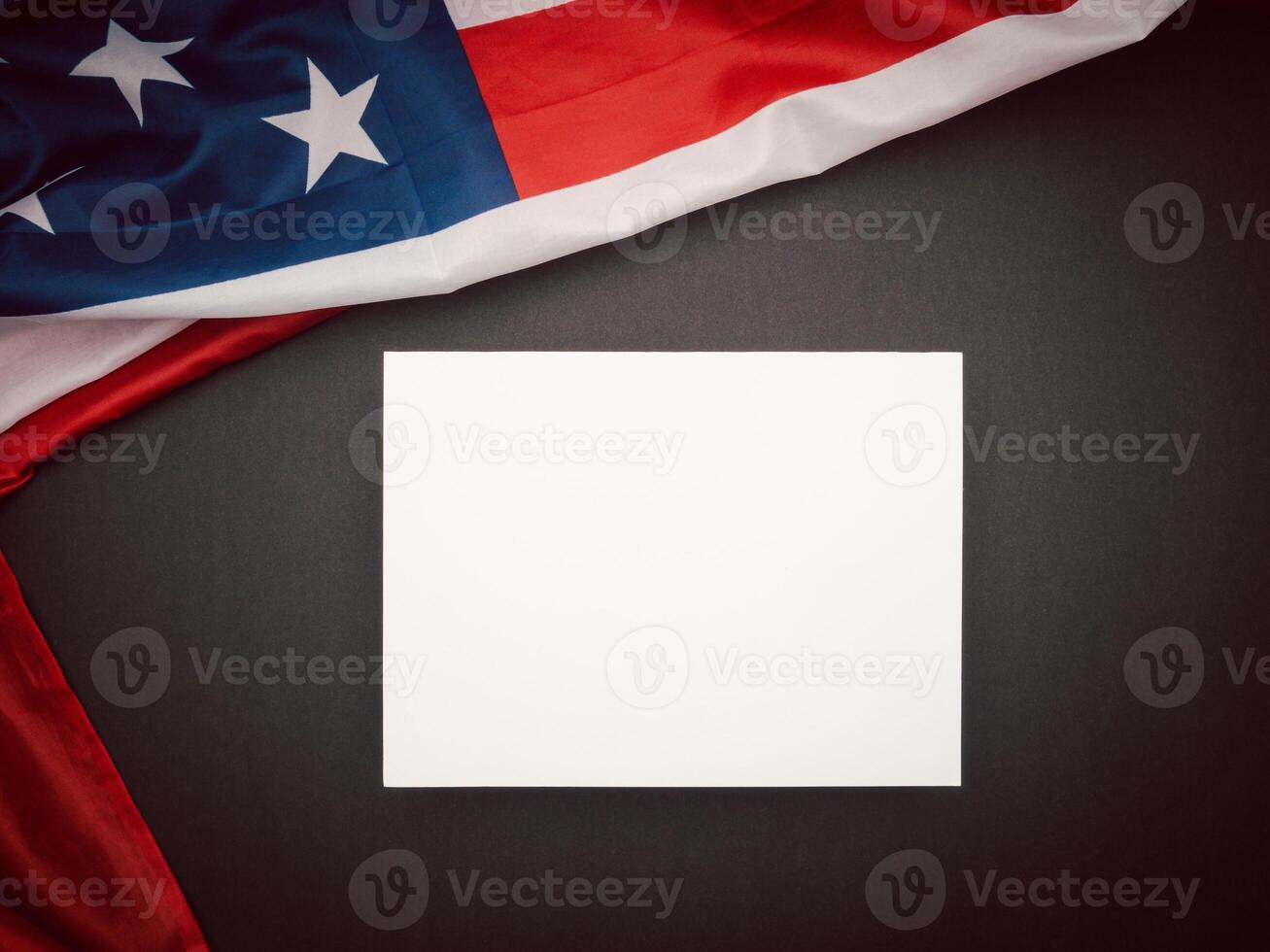 A part of the American flag and a blank white paper on a black background photo