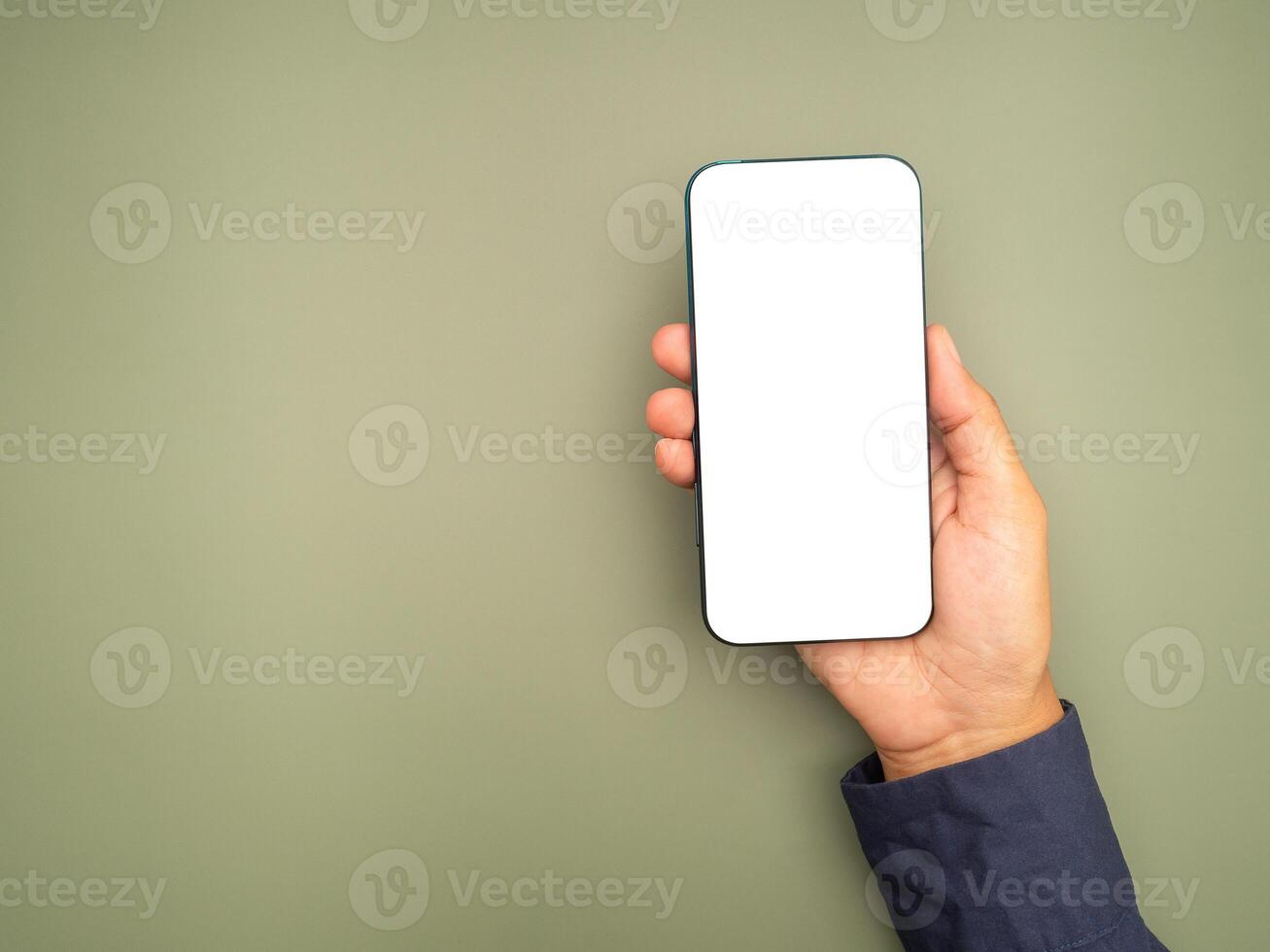 Top view of hand holding a white blank screen smartphone against a green background photo