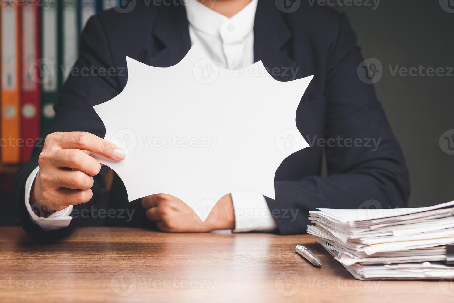 Businessman holding a blank white comic speech bubble while sitting at the table photo