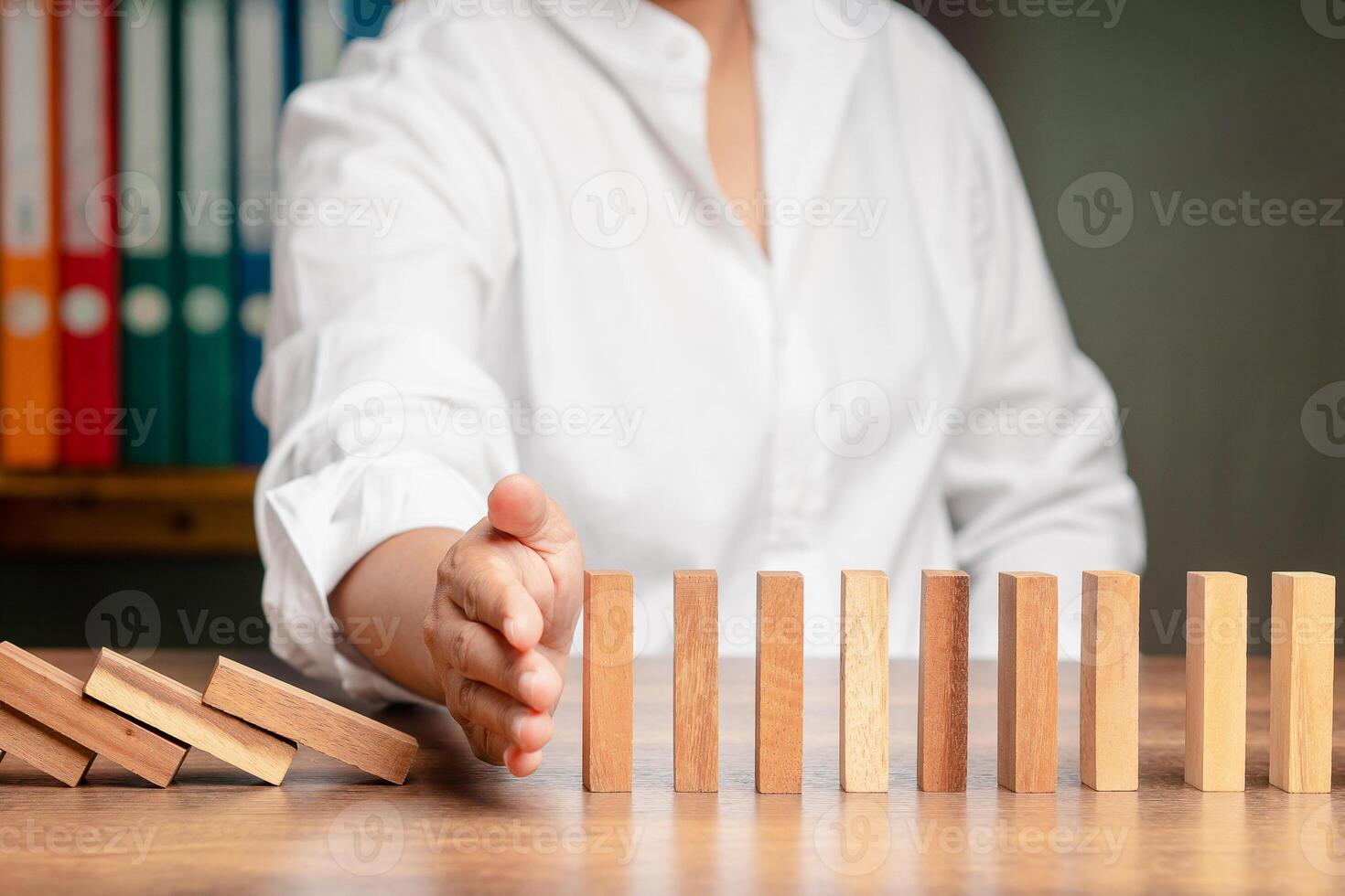 Hand of businessman stopping the domino business crisis effect before the business collapse. Close-up. photo