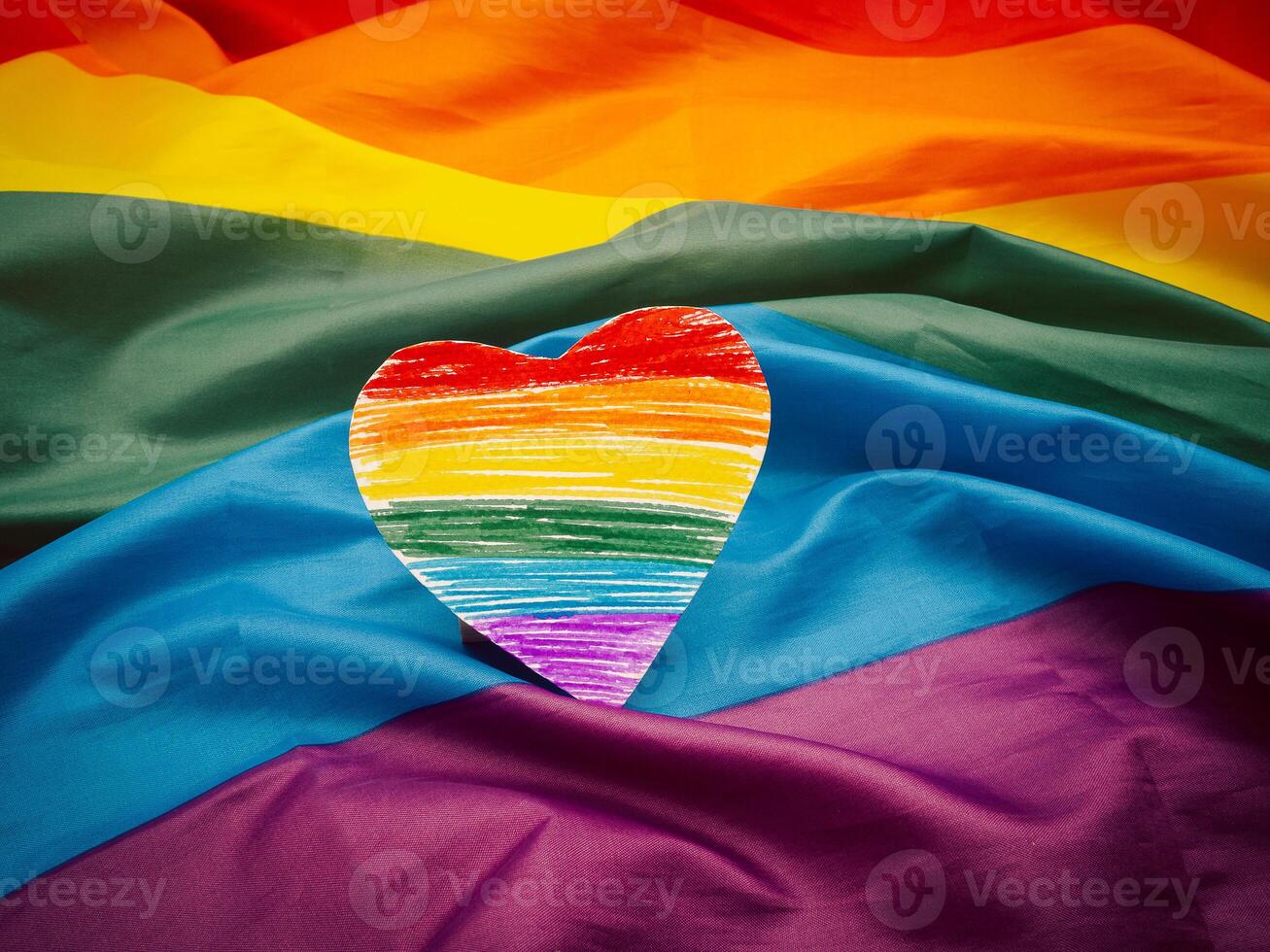 A rainbow heart shape symbol made from paper over the rainbow flag or LGBT flag photo