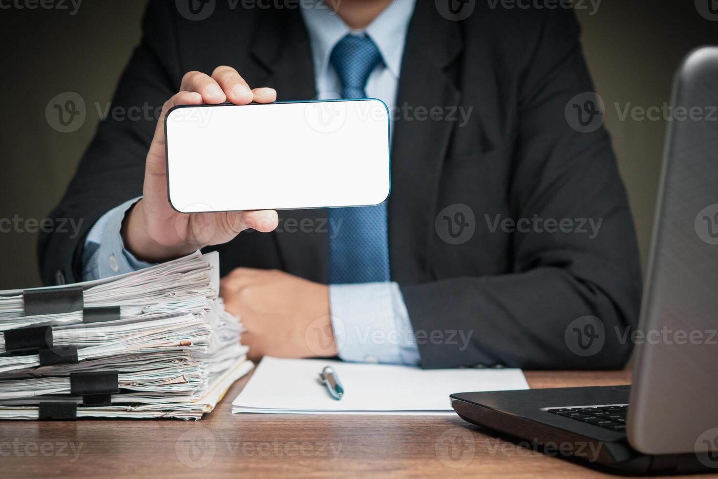 Close-up of a businessman holding a white blank screen smartphone while sitting at the table photo