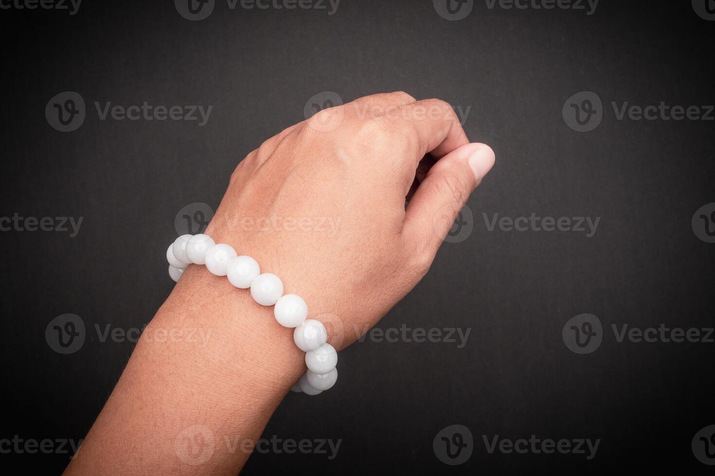 White jade bangle or bracelet on wrist against a black background photo