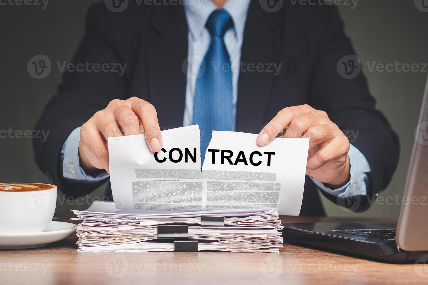 Businessman in a suit tearing up a contract while sitting at the table photo