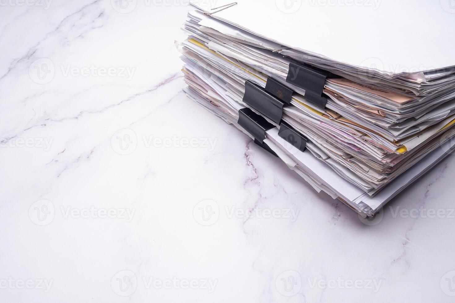 Stack of documents with binder clips on a marble table photo