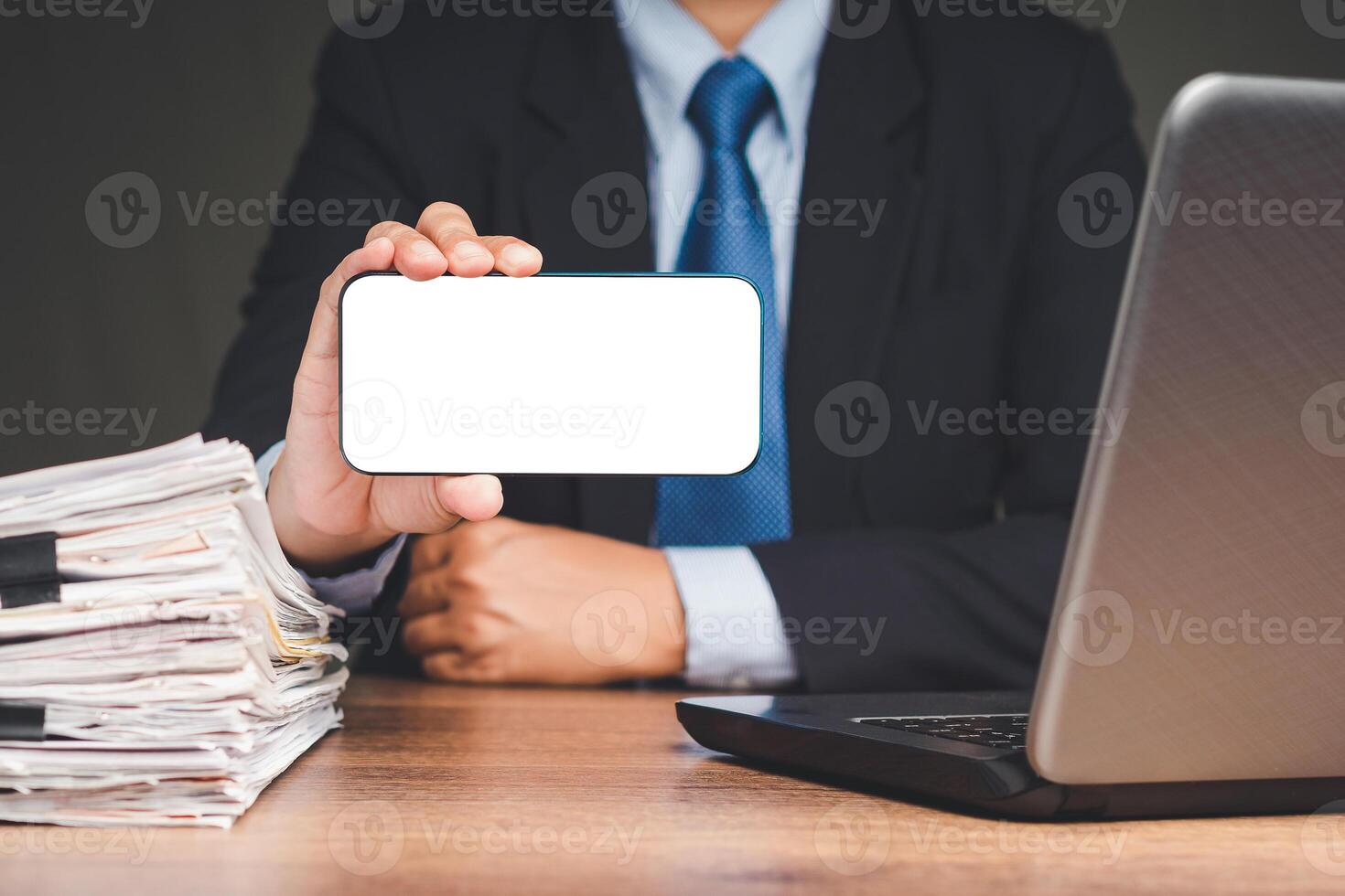 Businessman holding a white blank screen smartphone while sitting at the table photo