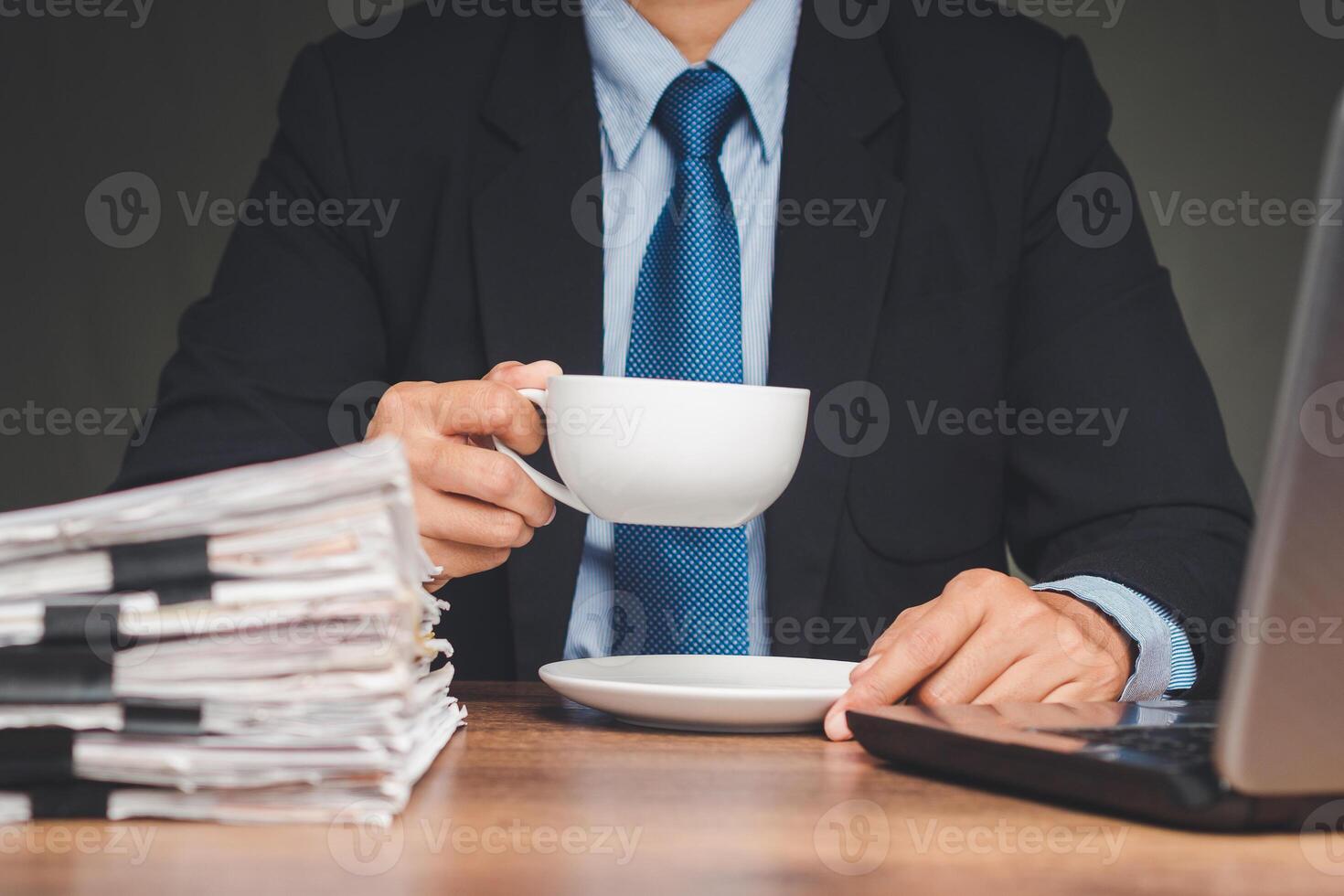 Businessman in a suit hand holding a cup of coffee while sitting working at the table photo
