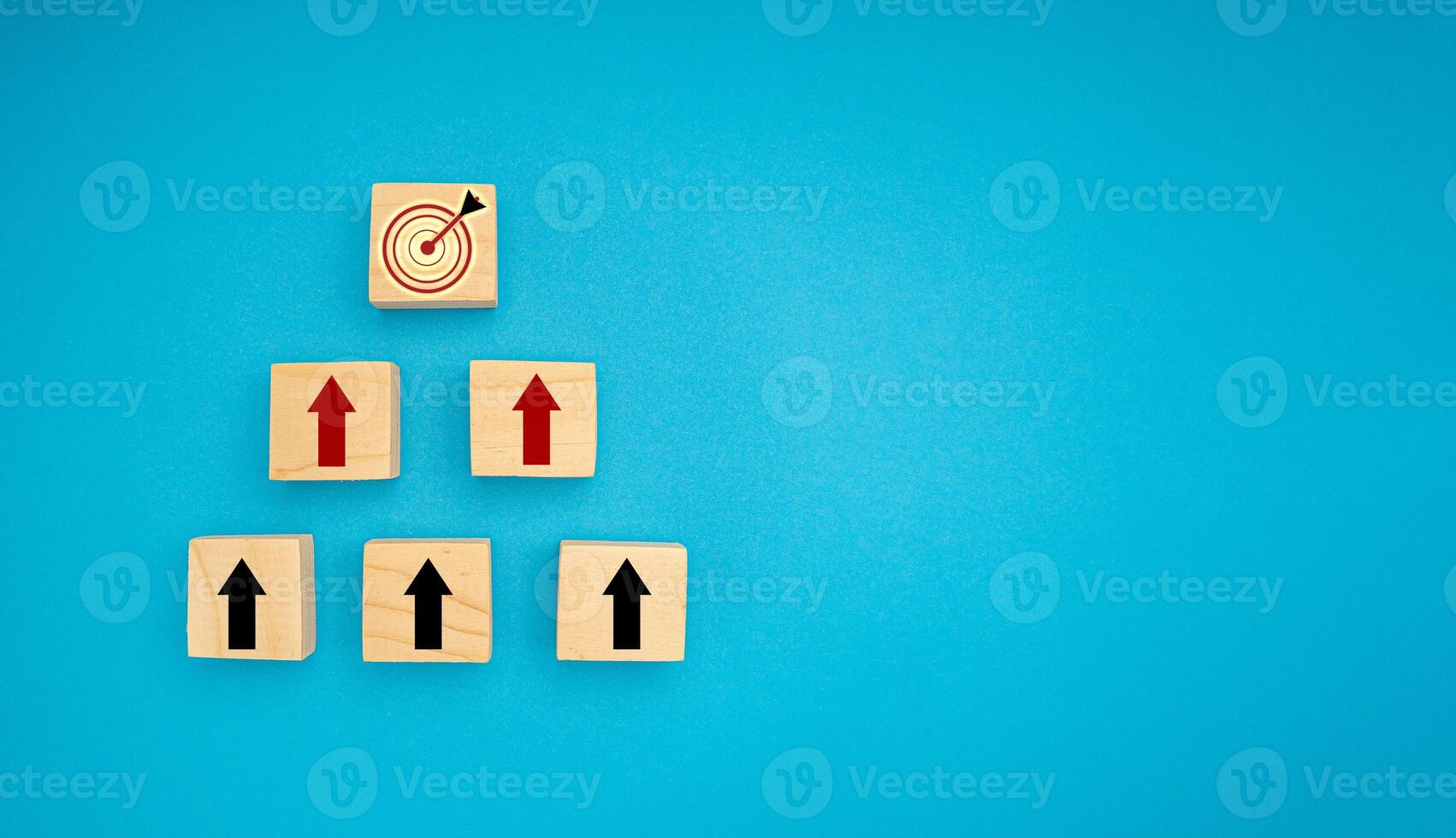 Wooden blocks with black and red arrows point to the dartboard icon on a blue background photo