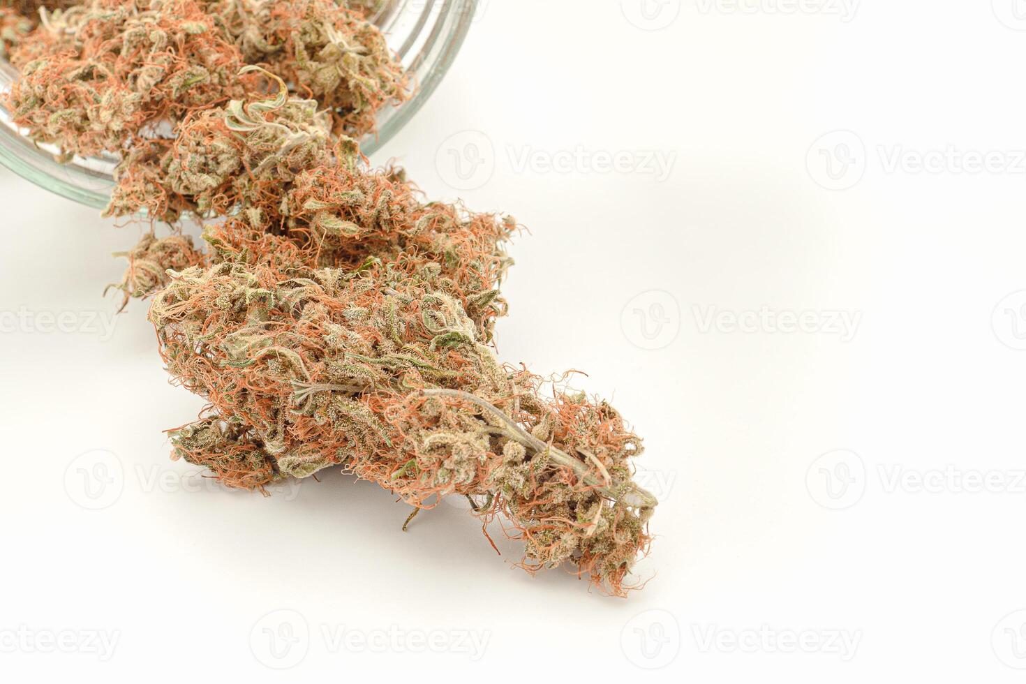 Dry marijuana buds outside of a jar on a white background photo