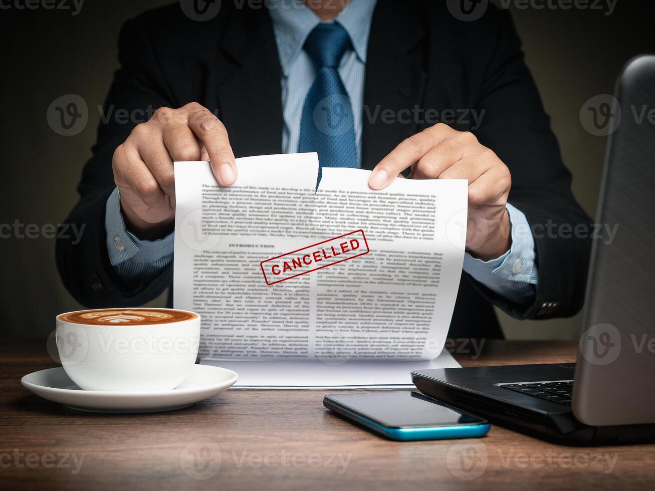 Businessman in a suit tearing up a canceled contract while sitting at the table. Close-up. photo