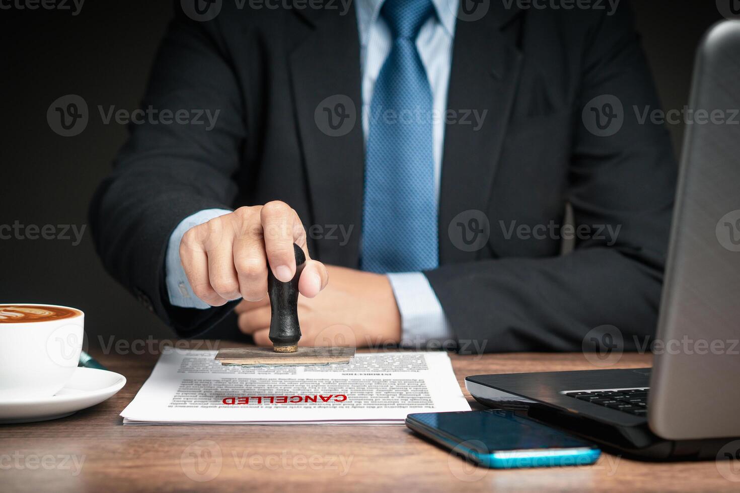 A businessman in a suit stamped for canceled documents while sitting at the table photo