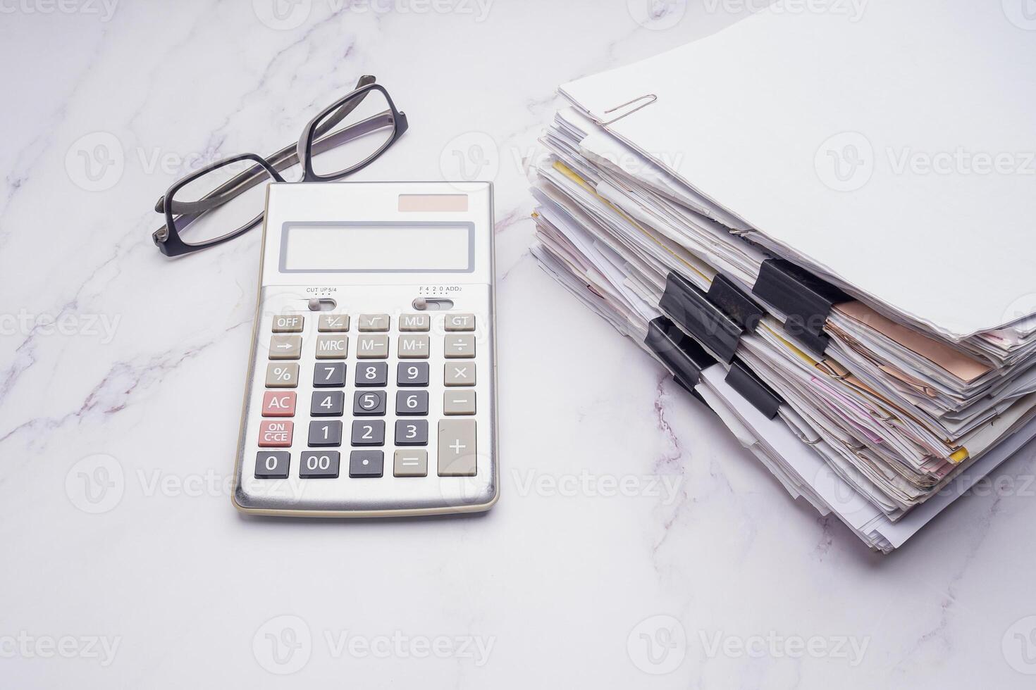 Stack of documents with binder clips, calculator on a marble table photo