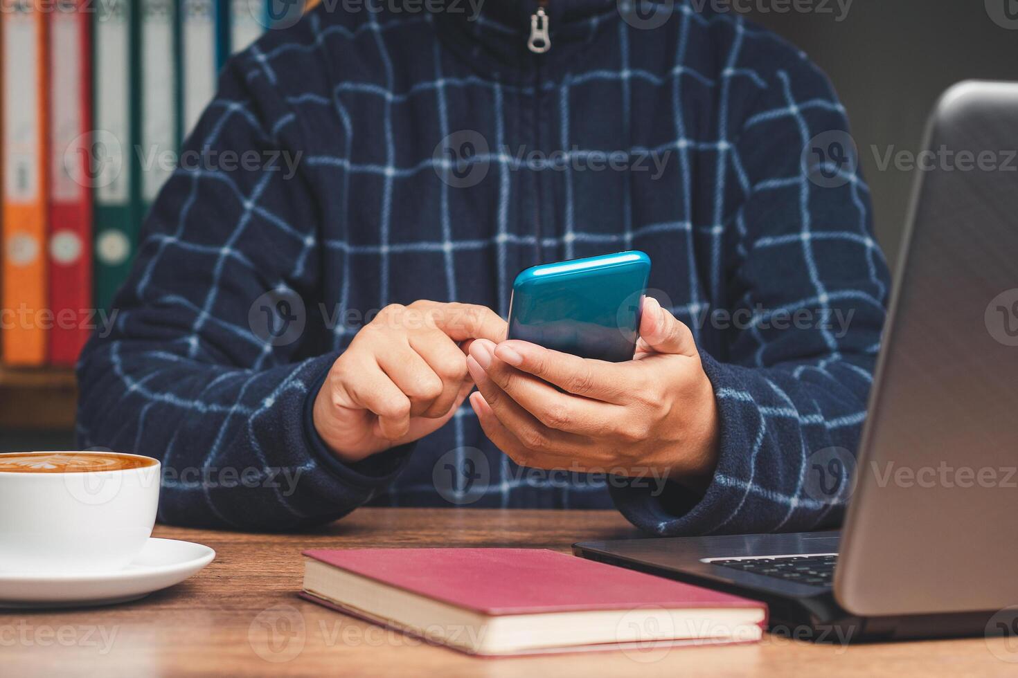 Businessman in a sweater using a smartphone while sitting at the table in the office photo