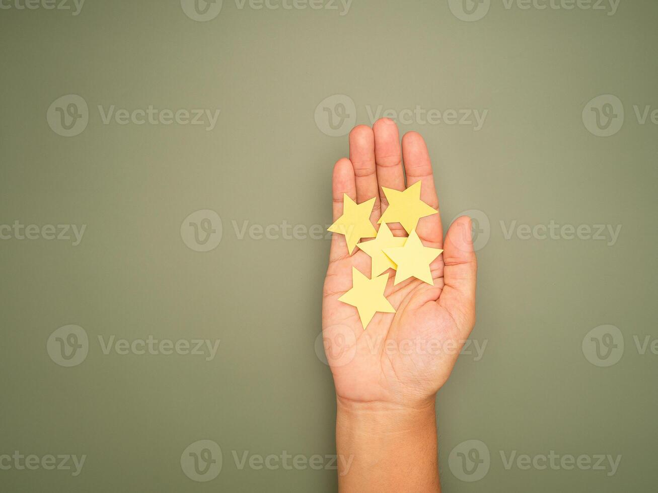 Top view of yellow paper cut in a star shape on the palm with a green background photo