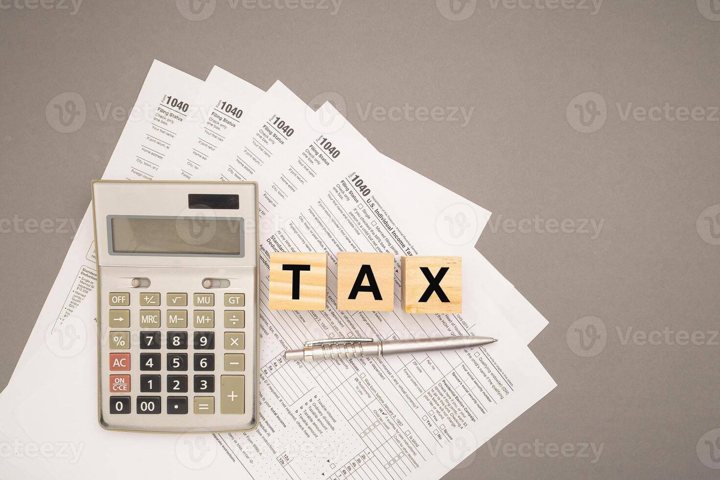 Top view of wooden cubes with the letter TAX over TAX form on a gray background. photo