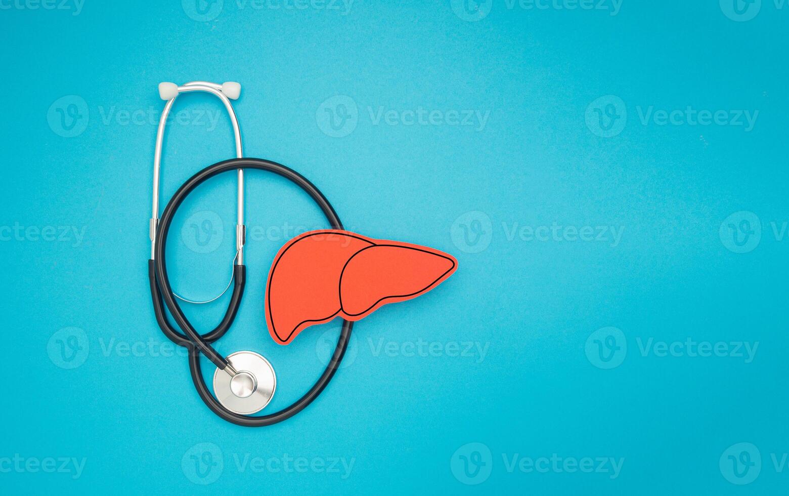 A stethoscope and a red liver shape symbol on a blue background photo