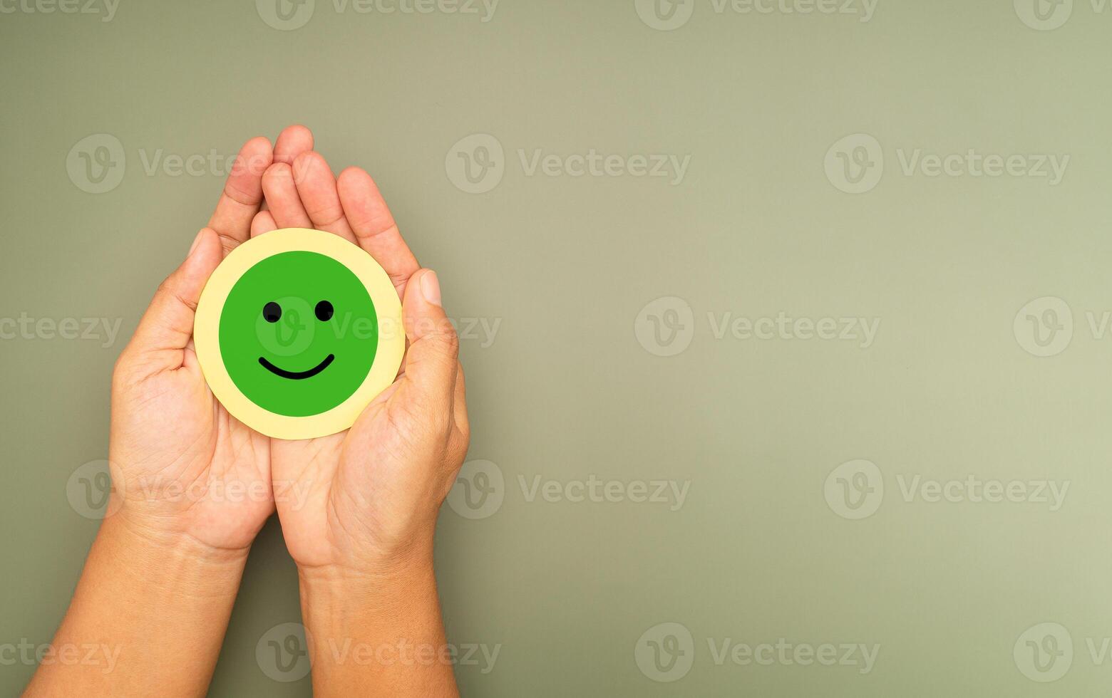 Green happy smile face in hands with a green background photo