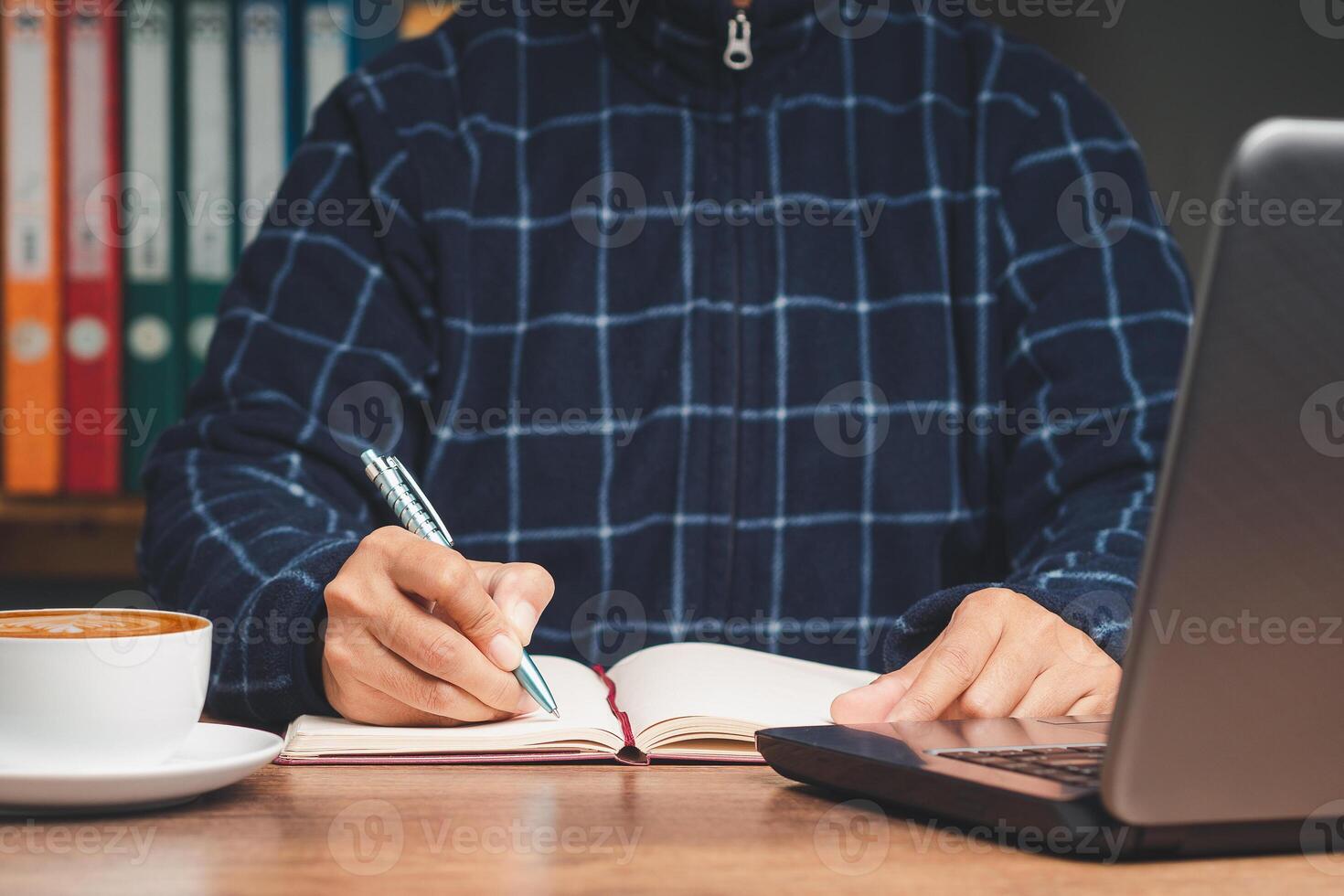 Hand holding a pen writing on a notebook on the desk. photo