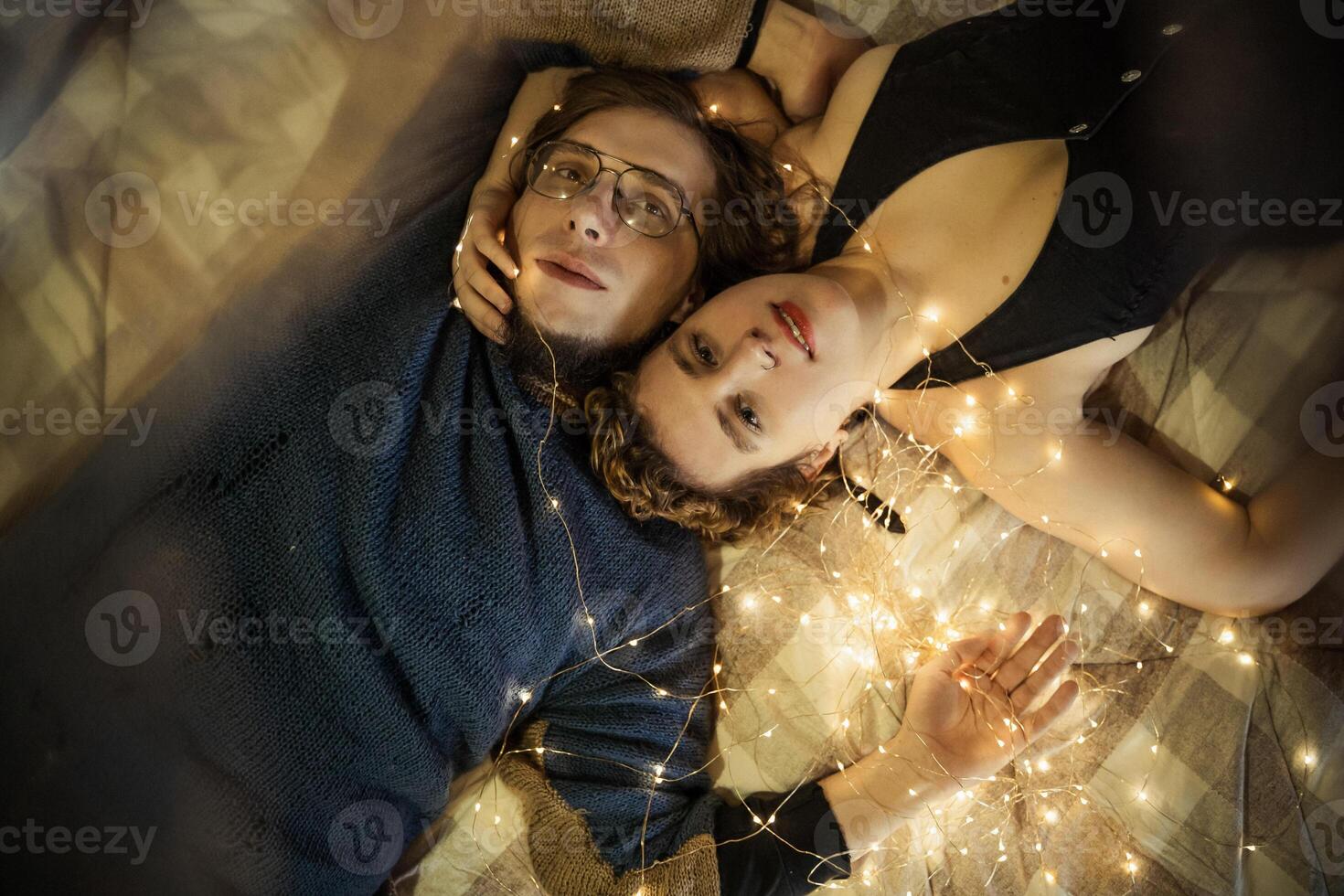 Couple enjoying intimate moments surrounded by warm fairy lights in a cozy setting photo