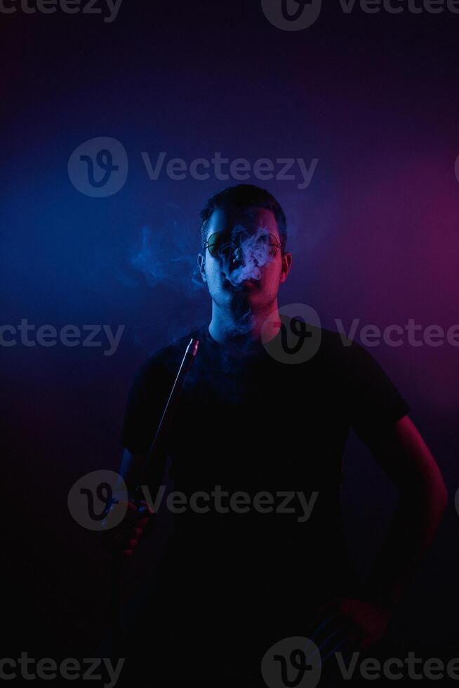 Man enjoys a moment of tranquility while smoking in neon-lit hookah bar atmosphere photo