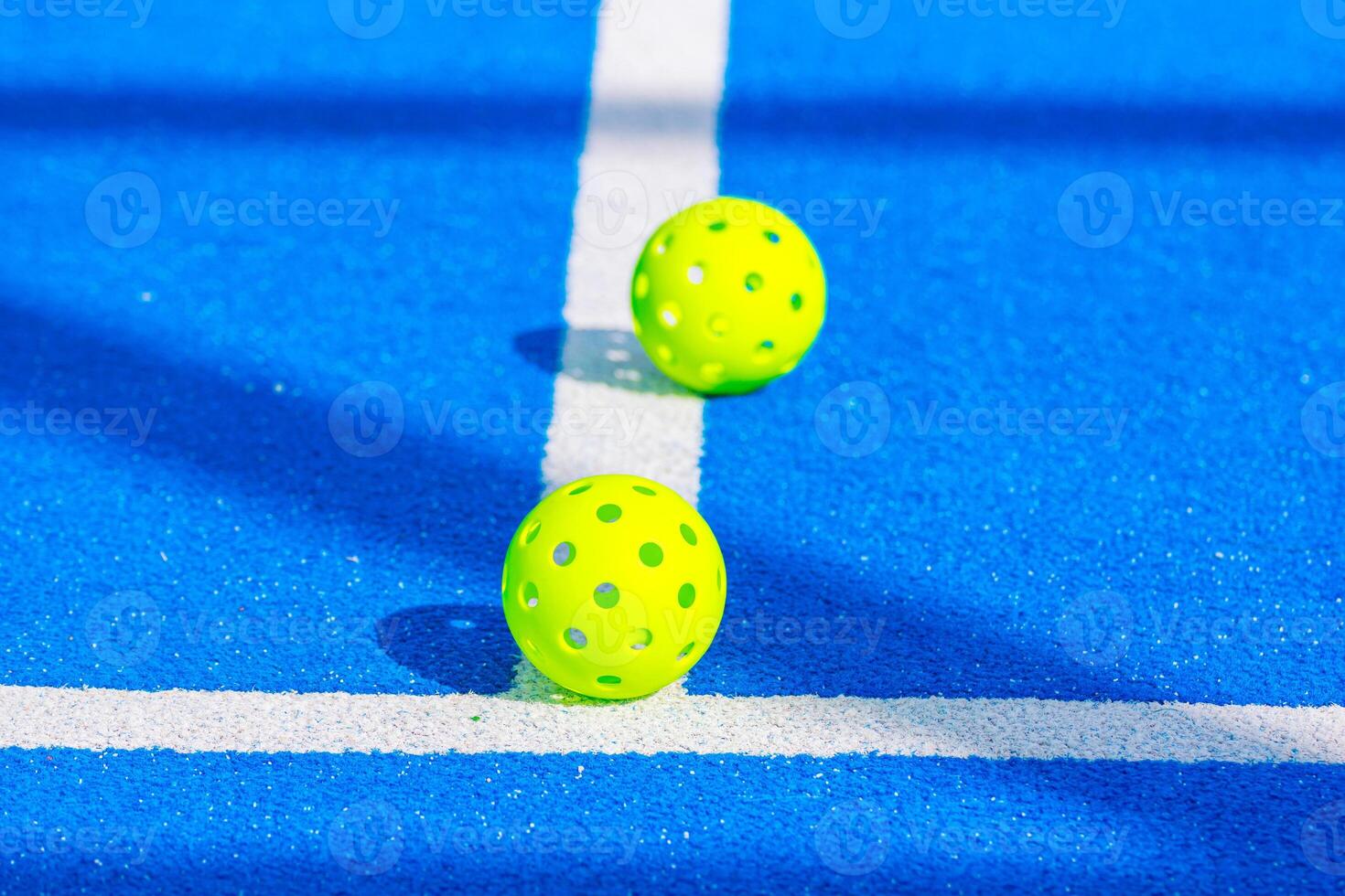 two pickleball balls on a blue court seen from close range photo