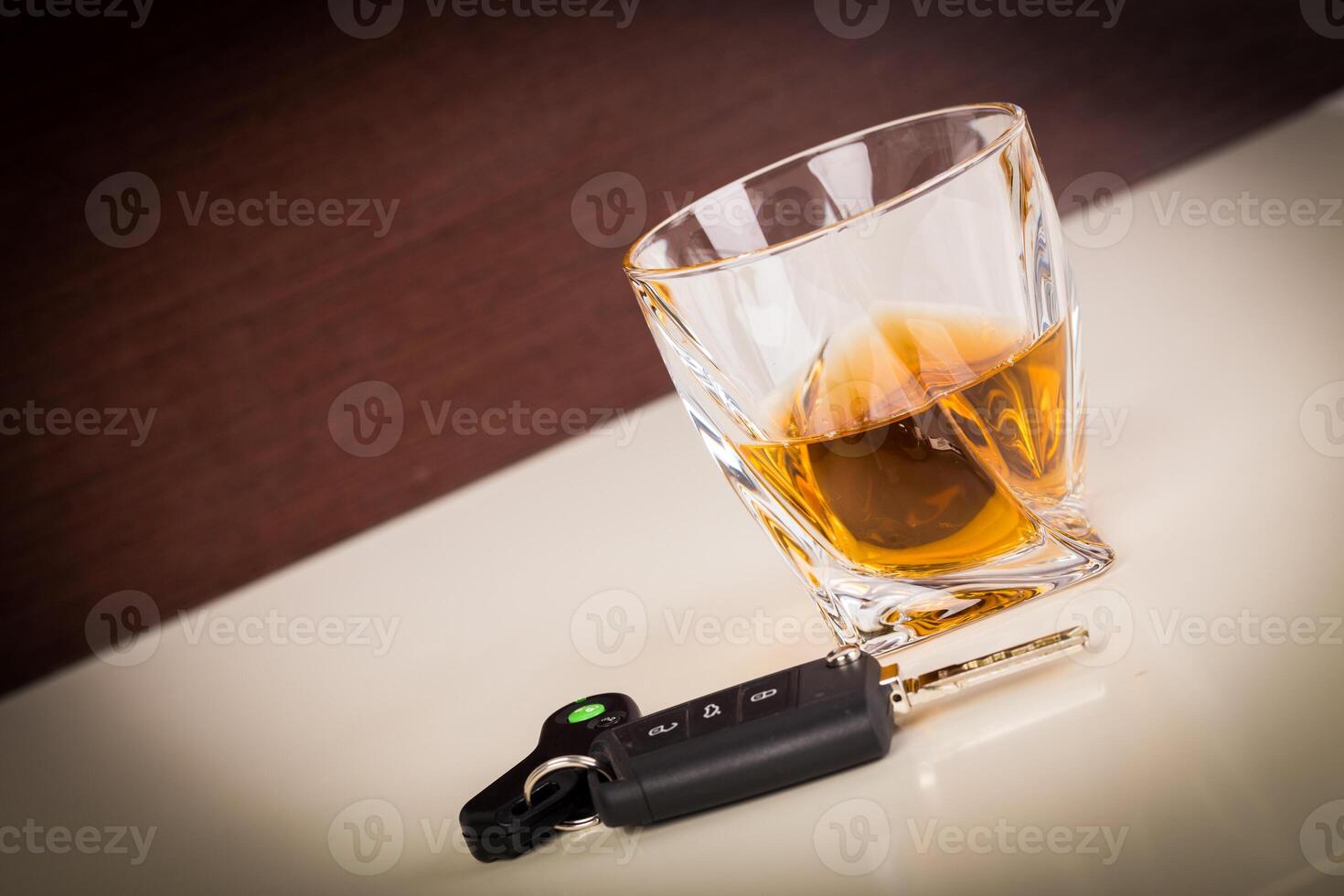 Glass with cognac or whiskey and car keys on table photo