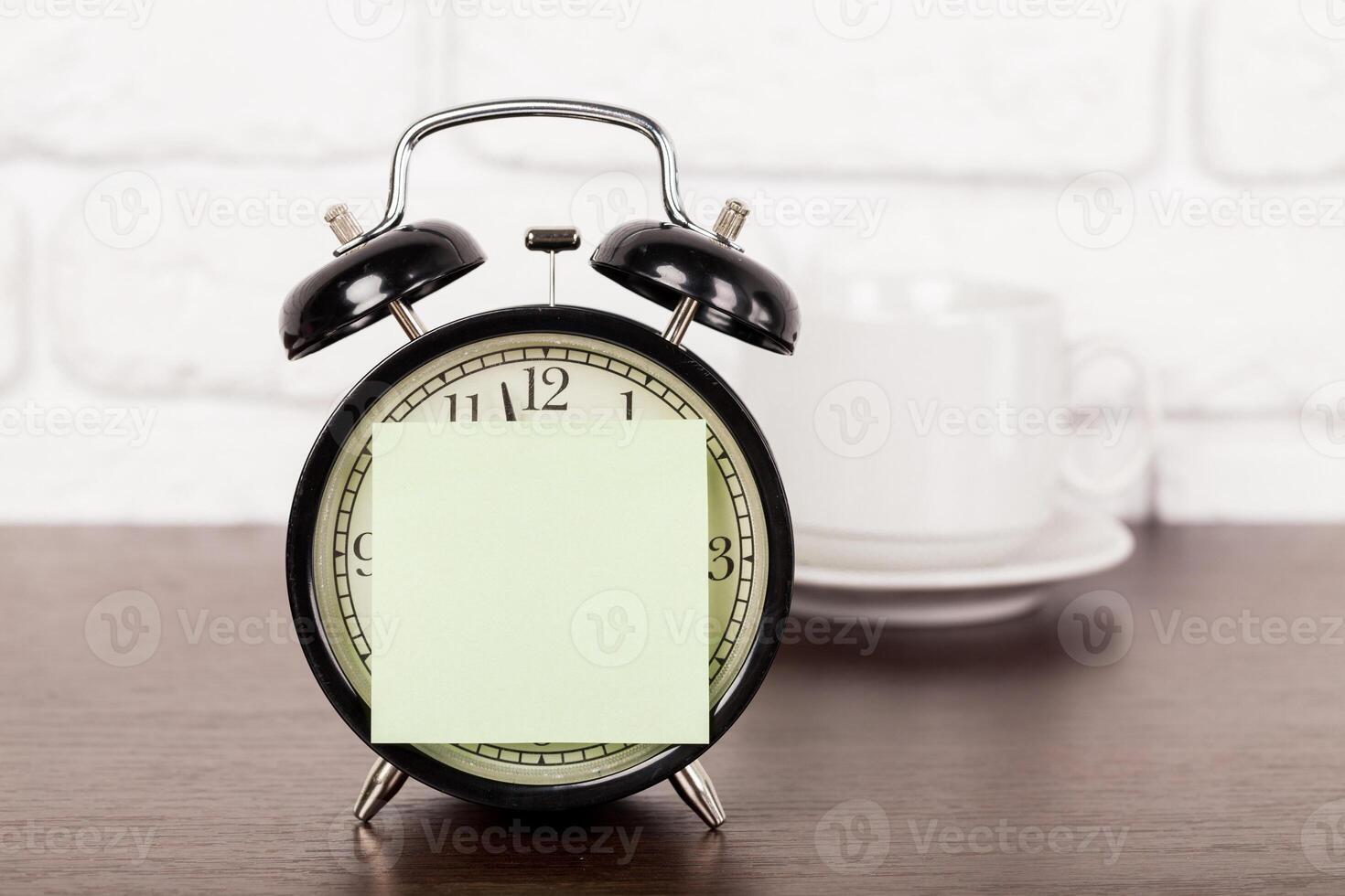 Reminder note and black old-fashioned alarm clock photo