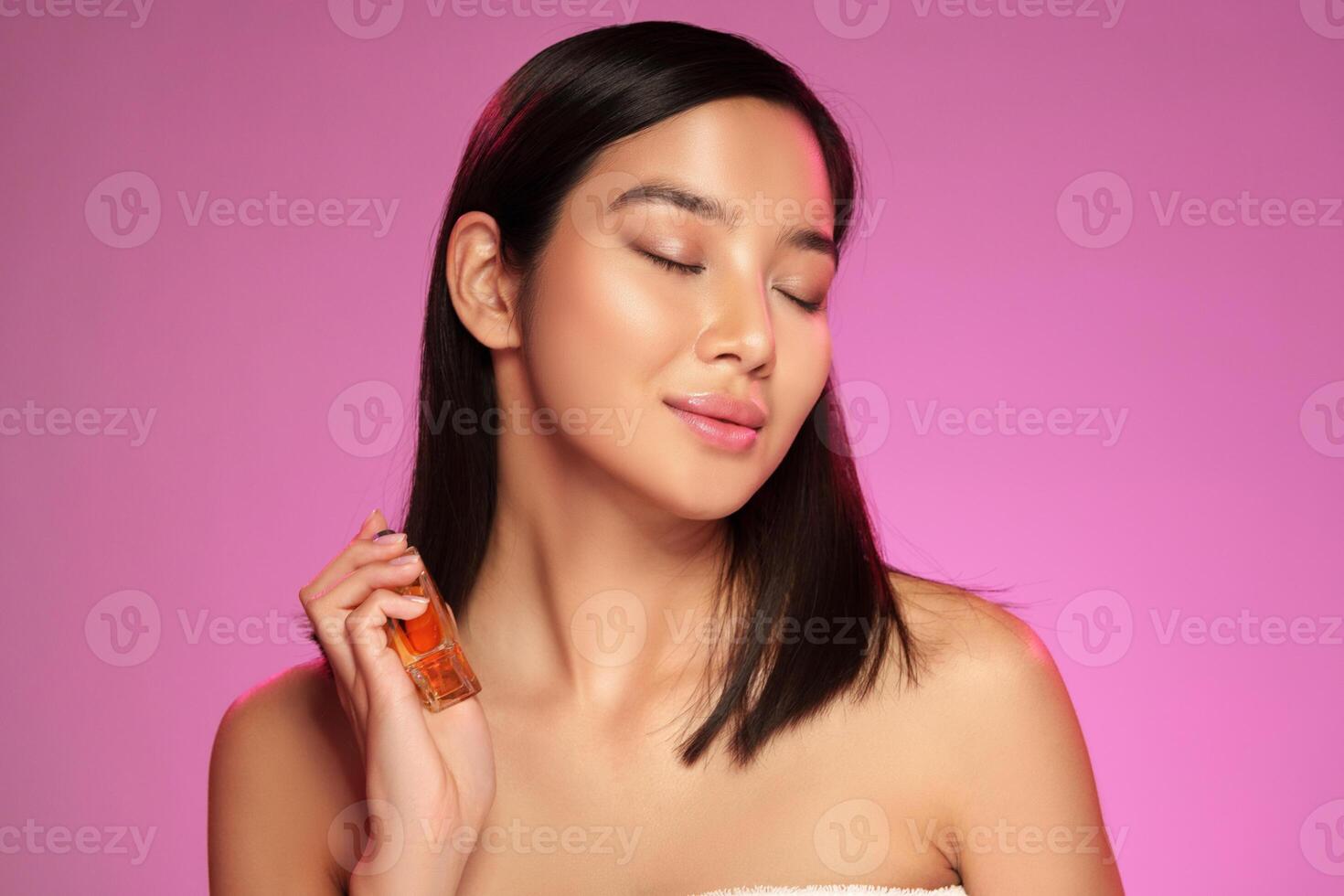 Model demonstrating skincare product application in a bright pink studio setting photo