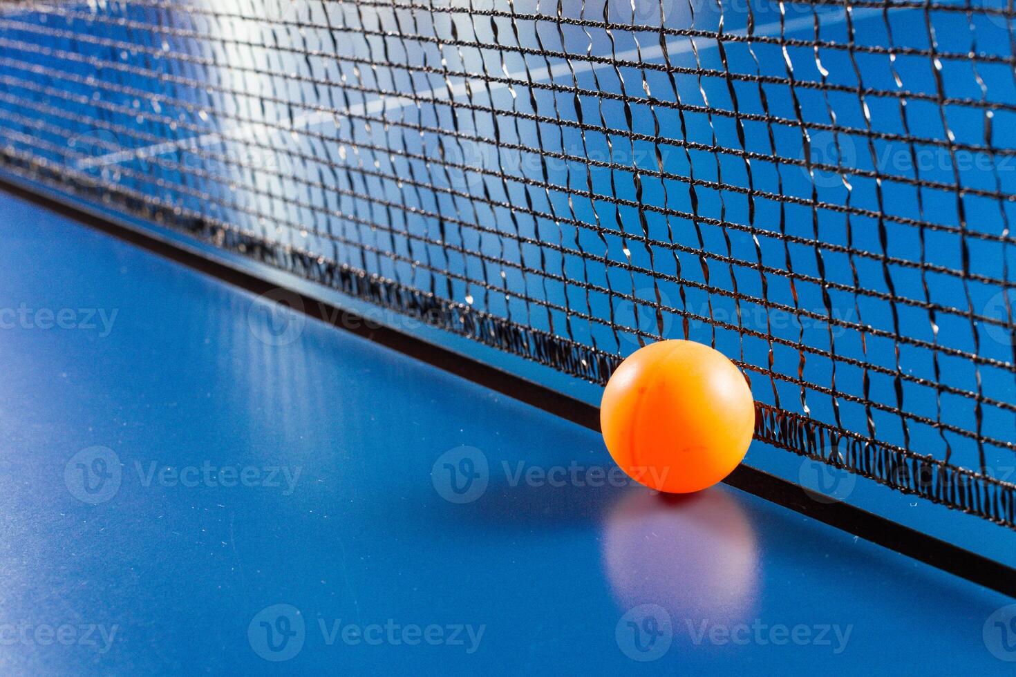 Table tennis ball near the net on blue table photo