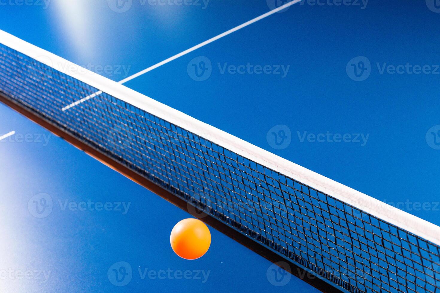 Table tennis ball near the net on blue table photo