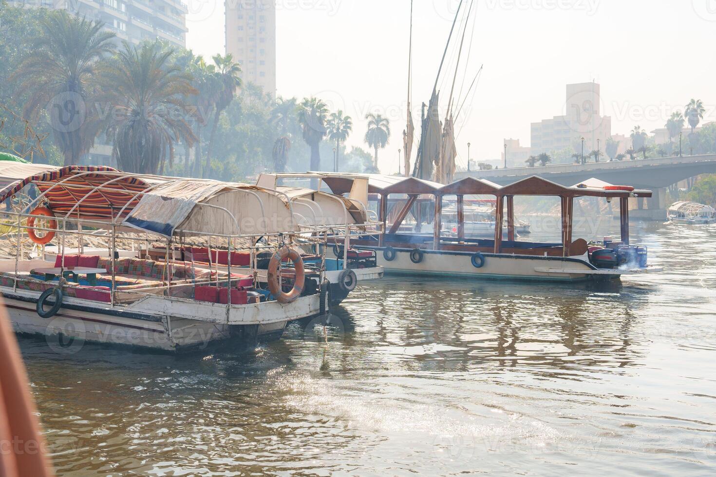 Vessels moored on the Nile River during a serene morning in Cairo with city skyline in the background photo