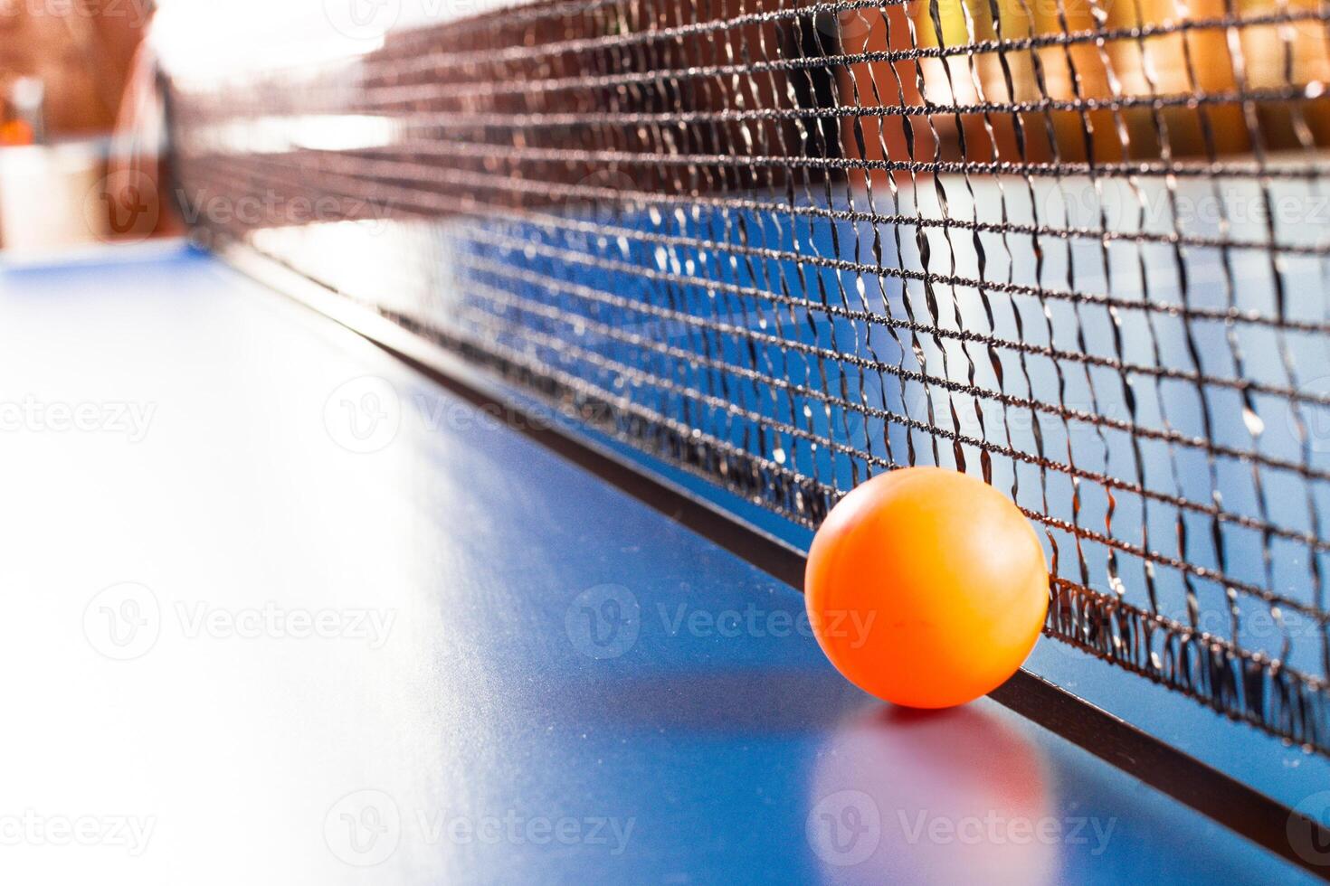 Table tennis ball near the net on blue table photo
