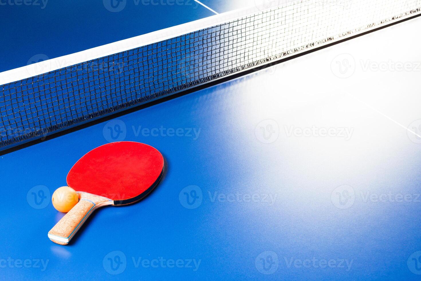 Two ping pong rackets and ball on blue table photo