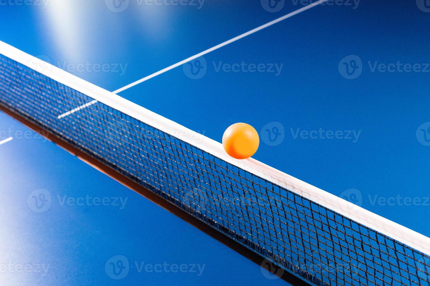 Table tennis ball near the net on blue table photo